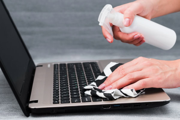 mãos mostrando como limpar o notebook