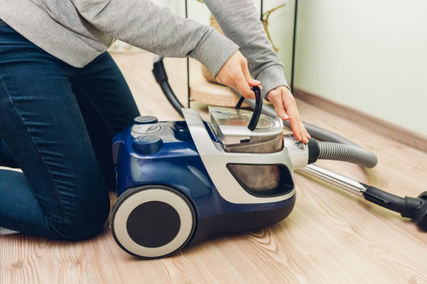 Pessoa puxando reservatório do aspirador de pó para limpar.
